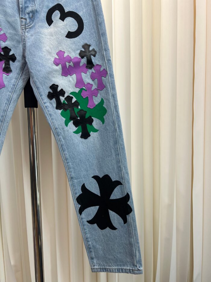 Jeans denim chiari con croci colorate, numero 3 nero e dettagli streetwear vibranti.