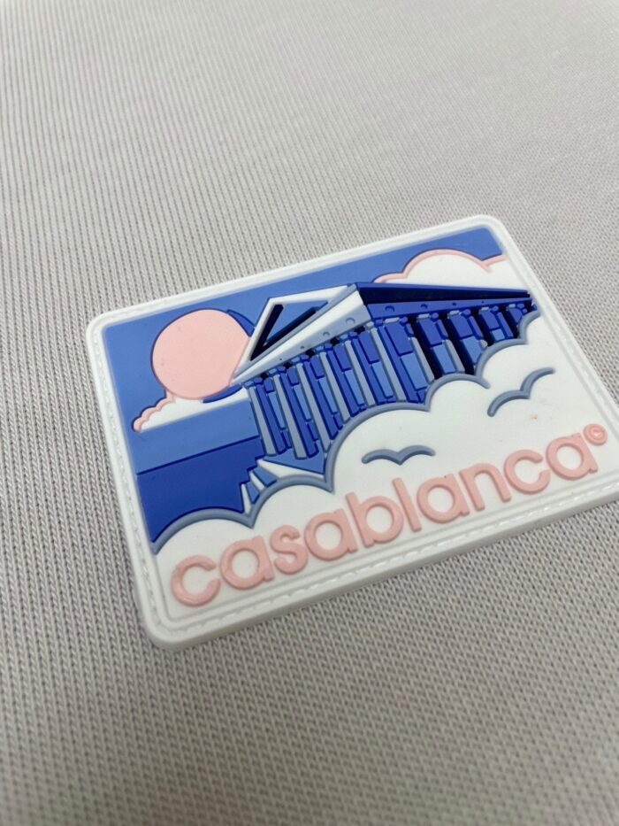 Patch artistico con colonne, sole rosa e testo “Casablanca” in stile giocoso.
