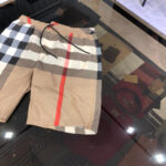 Shorts estivi patchwork con striscia rossa, stile trendy e comfort casual, riflessi su superficie lucida.