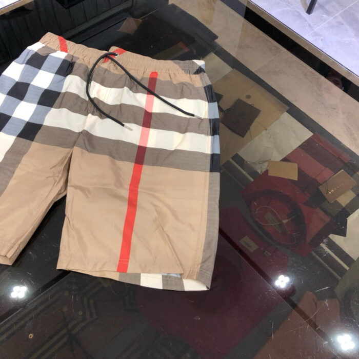 Shorts estivi patchwork con striscia rossa, stile trendy e comfort casual, riflessi su superficie lucida.