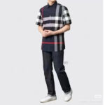 Persona in jeans scuri e maglietta a quadri colorata con sneakers bianche, stile casual e moderno.