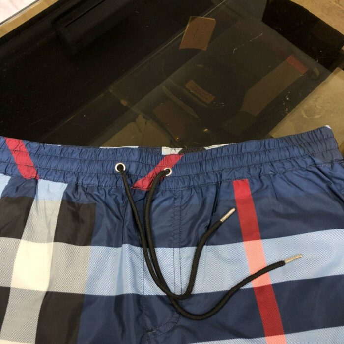 Shorts da spiaggia blu a quadri con elastico e laccio, perfetti per il mare e il relax.