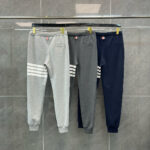 Jogger sportivi in grigio, blu navy, dettagli a righe su rastrelliera in stile casual.