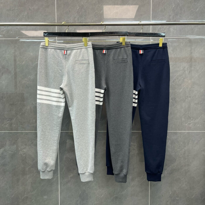 Jogger sportivi in grigio, blu navy, dettagli a righe su rastrelliera in stile casual.