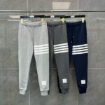 Jogger sportivi in grigio e navy con strisce bianche, stile athleisure, esposti su porta abiti.