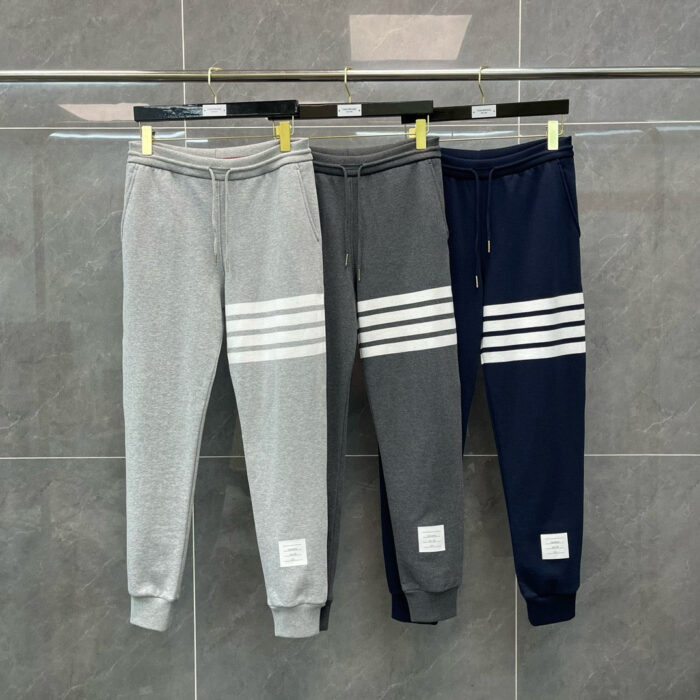 Jogger sportivi in grigio e navy con strisce bianche, stile athleisure, esposti su porta abiti.