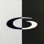 Logo ricamato bianco e nero su sfondi contrastanti, tessuti chiari e scuri, design elegante e simmetrico.