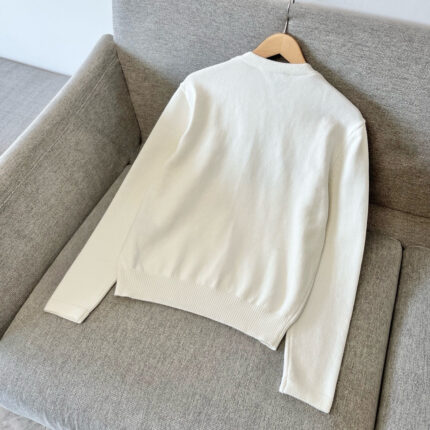 Maglione bianco minimalista su divano grigio, stile semplice e accogliente per il relax.