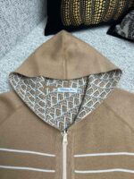Felpa beige con cappuccio aperto, dettagli geometrici interni e strisce sportive eleganti.