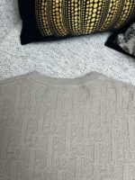 Maglione beige in maglia cable con cuscini decorativi in stile caldo e accogliente.