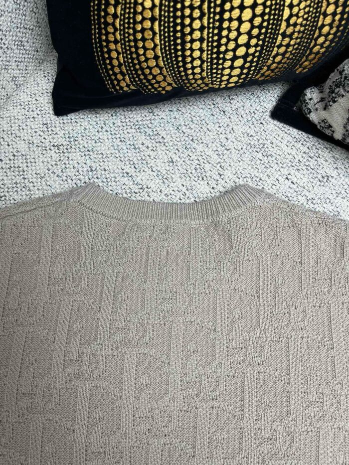 Maglione beige in maglia cable con cuscini decorativi in stile caldo e accogliente.