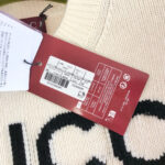 Maglione in lana crema con logo nero e etichette di marca, nuovo e di alta qualità.