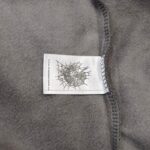 Etichetta tessile con ragnatela su morbido tessuto grigio, di alta qualità e stile elegante.