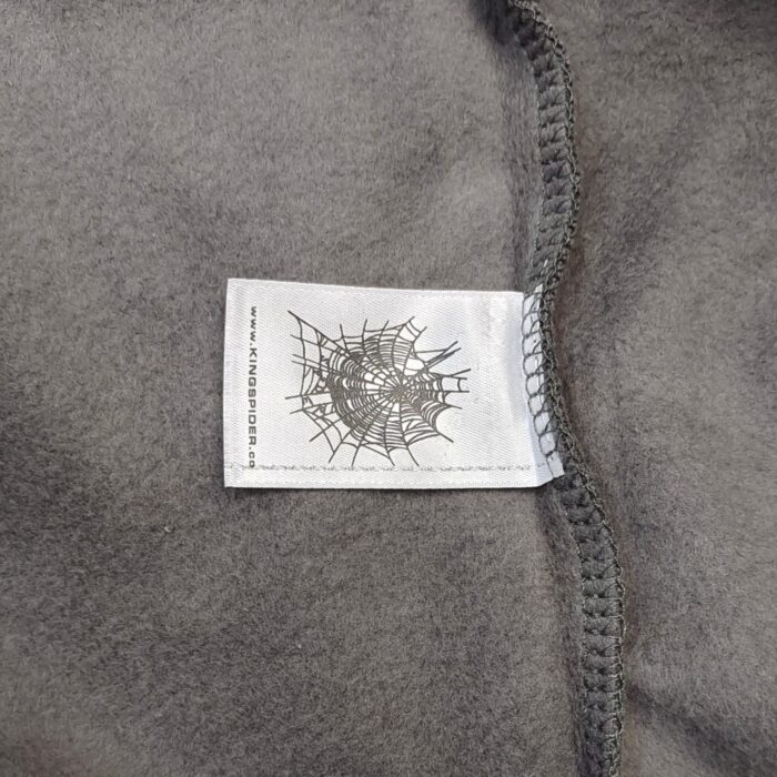 Etichetta tessile con ragnatela su morbido tessuto grigio, di alta qualità e stile elegante.