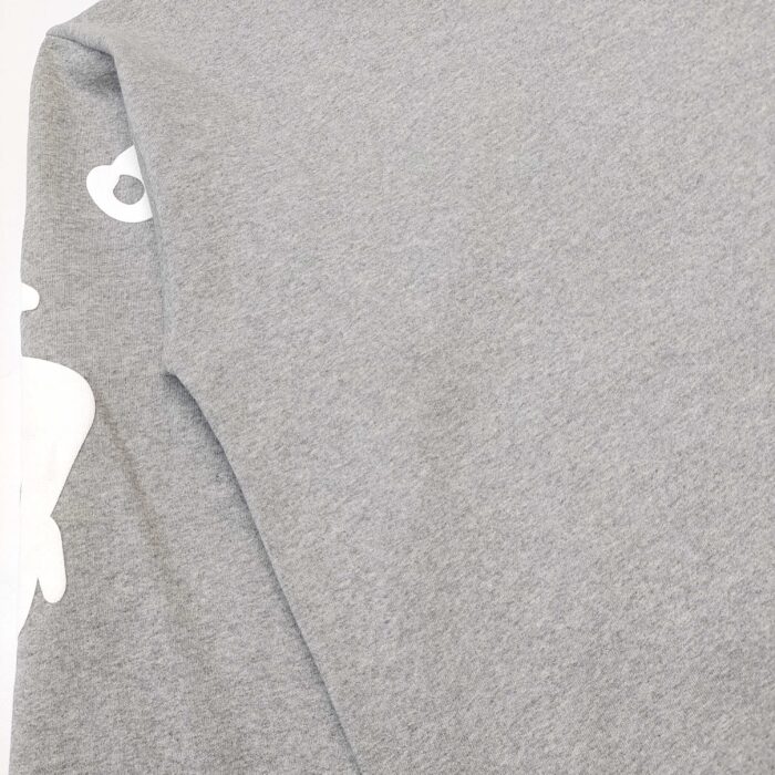 Maglia oversized grigia con graphic sulla manica, stile streetwear casual e trendy.
