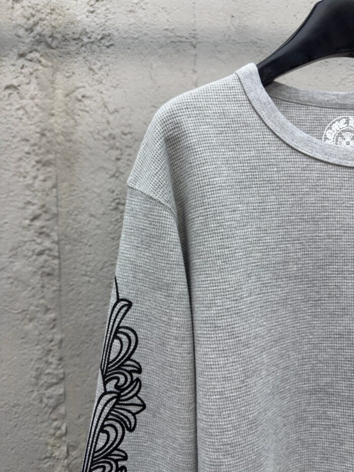 Felpa oversized grigia con dettagli grafici neri e stile urbano, perfetta per un look casual.