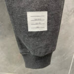 Polsino grigio con etichetta con dettagli su cura e composizione del tessuto.