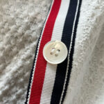 Maglia sportiva con bottone e fascia colorata bianca, rossa e blu, dettaglio di abbigliamento casual.