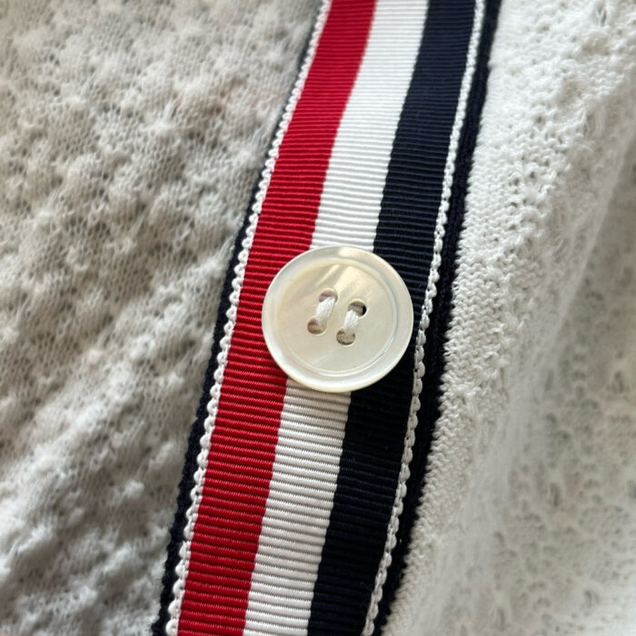 Maglia sportiva con bottone e fascia colorata bianca, rossa e blu, dettaglio di abbigliamento casual.