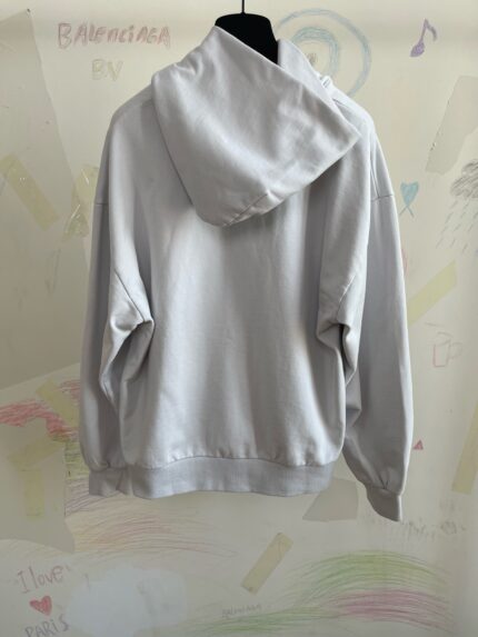 Felpa oversize grigia casual su sfondo artistico e colorato, perfetta per look comodi e moderni.