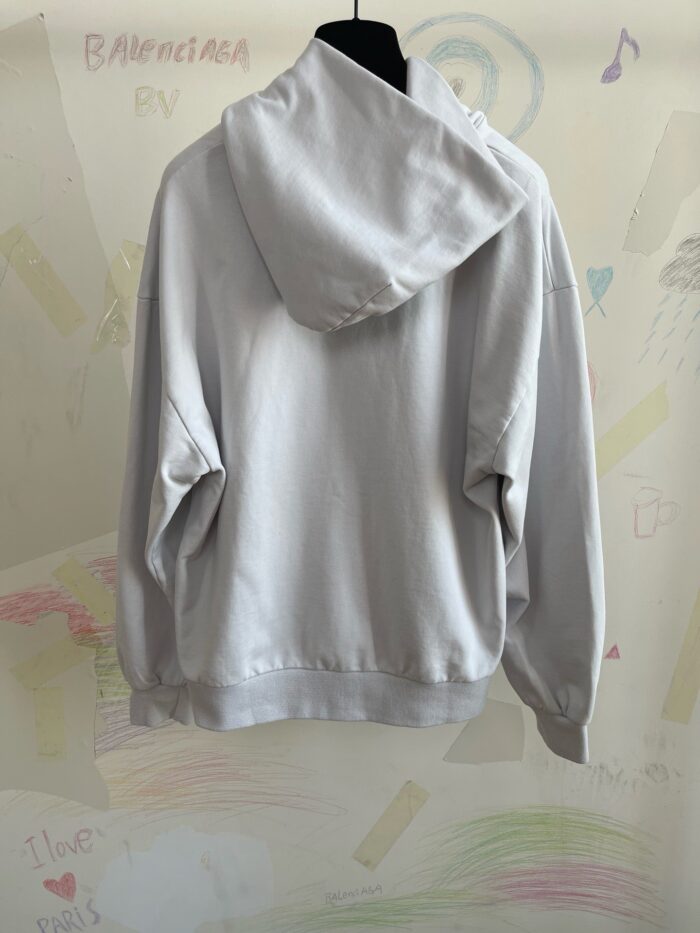 Felpa oversize grigia casual su sfondo artistico e colorato, perfetta per look comodi e moderni.