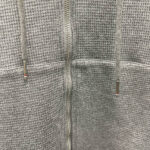 Felpa grigia con cerniera, cordoncini braidati e dettagli metallici, comoda e versatile per il casual.