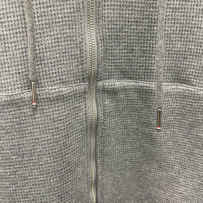 Felpa grigia con cerniera, cordoncini braidati e dettagli metallici, comoda e versatile per il casual.
