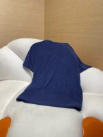 Maglietta blu casual sul divanetto moderno in ambientazione accogliente e di stile.