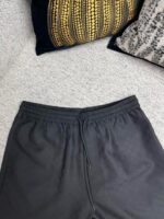 Pantaloni sportivi neri con cuscini decorativi eleganti in ambiente casalingo confortevole.