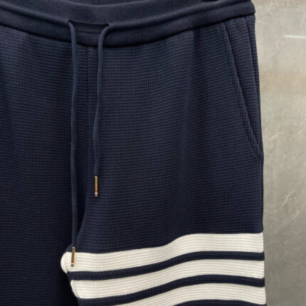 Pantaloni jogger navy con strisce bianche, elastico in vita e coulisse dorata, stile sportivo e versatile.