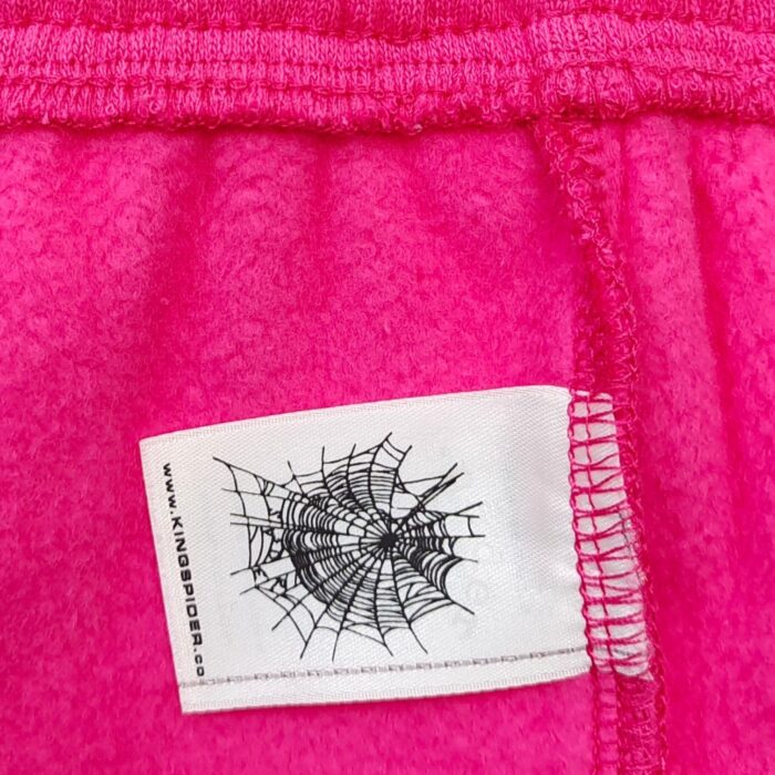 Cappotto rosa morbido con etichetta a ragnatela e ragno, stile giocoso e originale.