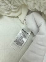 Coperta bianca in pile con etichetta di cura, perfetta per il comfort domestico.