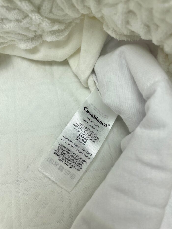 Coperta bianca in pile con etichetta di cura, perfetta per il comfort domestico.