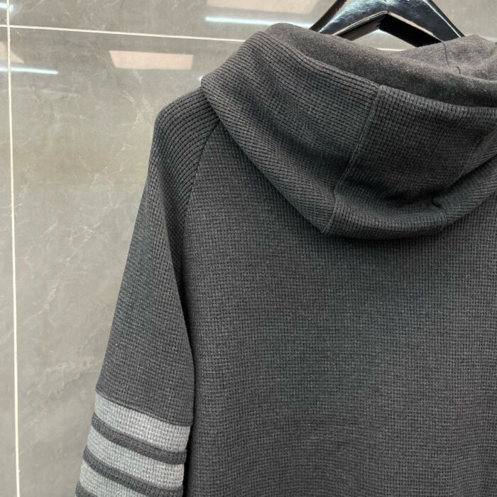 Felpa grigia sportiva con cappuccio e strisce sulle maniche, stile casual e moderno.