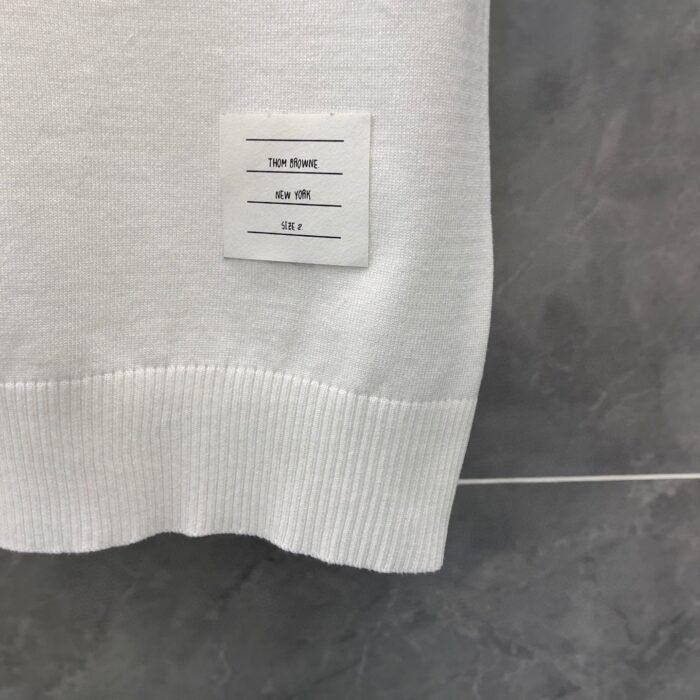 Maglietta bianca con etichetta minimalista e elegante, viscosa morbida su sfondo grigio scuro.