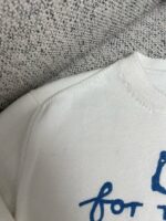 Maglione bianco casual con scritta blu, morbido e ideale per il relax quotidiano.