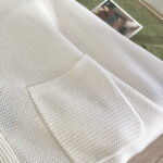 Vestito bianco con tasca, tessuto morbido e texture elegante per uno stile casual e confortevole.