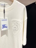 T-shirt Burberry crema e nera con logo ricamato, stile elegante e di lusso.