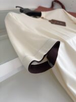 Camicia beige con polsino marrone scuro, tessuto leggero e stile elegante, versatile per ogni occasione.