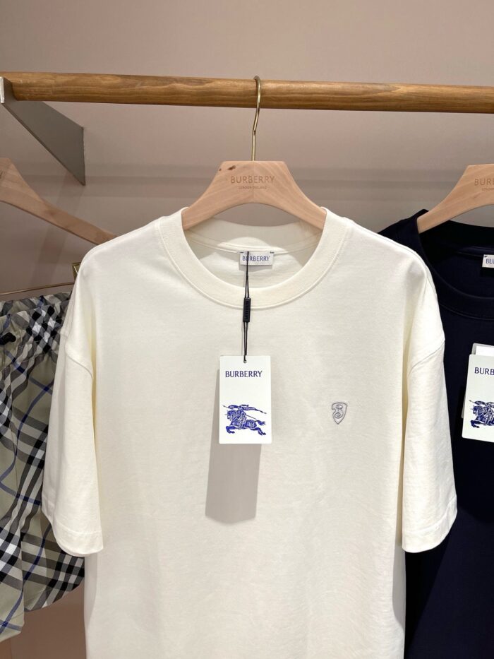 Maglietta cream con logo ricamato Burberry, elegante e versatile, esposta su appendiabiti in negozio.