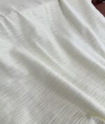 Tessuto bianco leggero e delicato, ideale per abbigliamento e decorazioni eleganti.