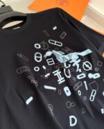 Maglietta nera con design blu astratto e dettagli di meccanica, stile creativo e moderno.