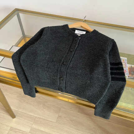 Cardigan cropped grigio con dettagli a righe nere, stile elegante e casual.