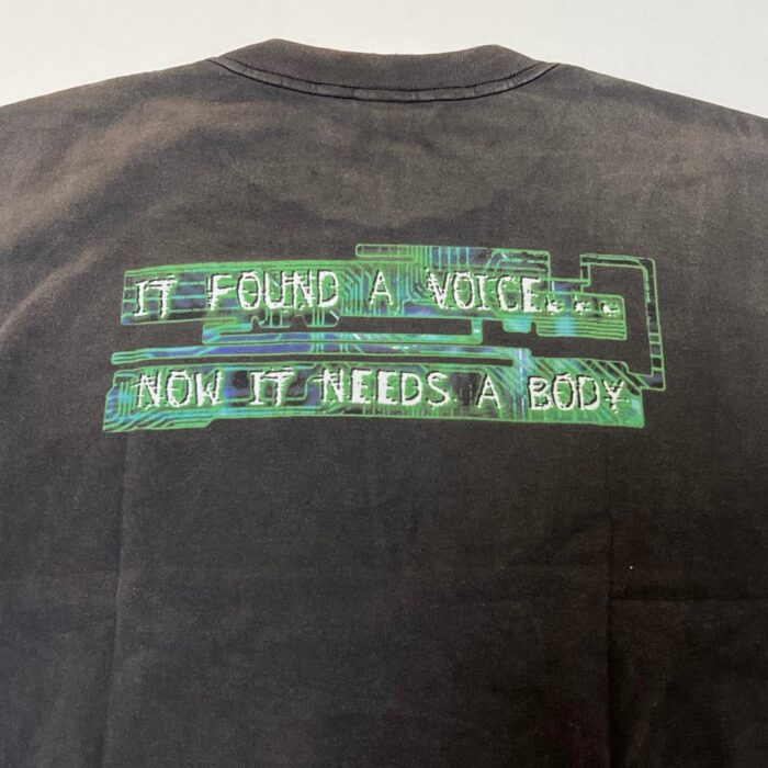 Maglietta nera con scritte neon e motivi circuitali, ideale per appassionati di cyberpunk e tecnologia.