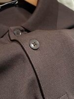 Polo marrone in cotone traspirante con colletto classico e bottoni neri lucidi.