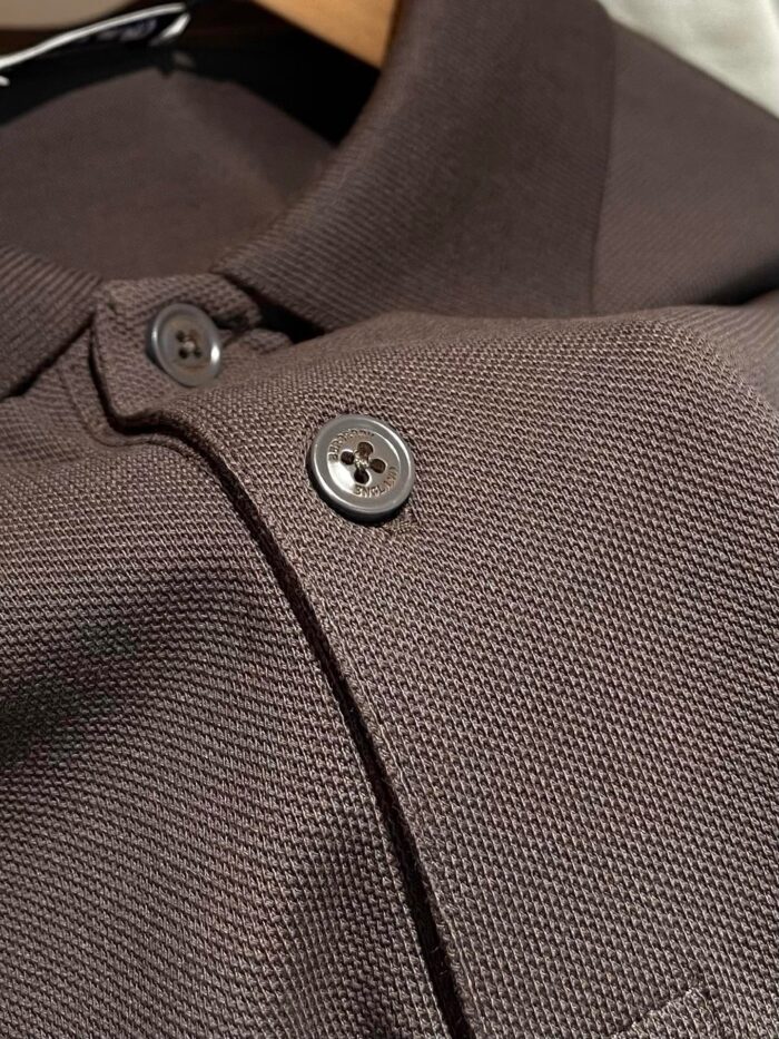 Polo marrone in cotone traspirante con colletto classico e bottoni neri lucidi.