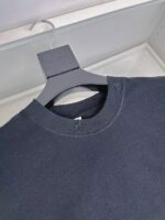 Maglietta nera minimalista su appendino in negozio, stile casual ed elegante.