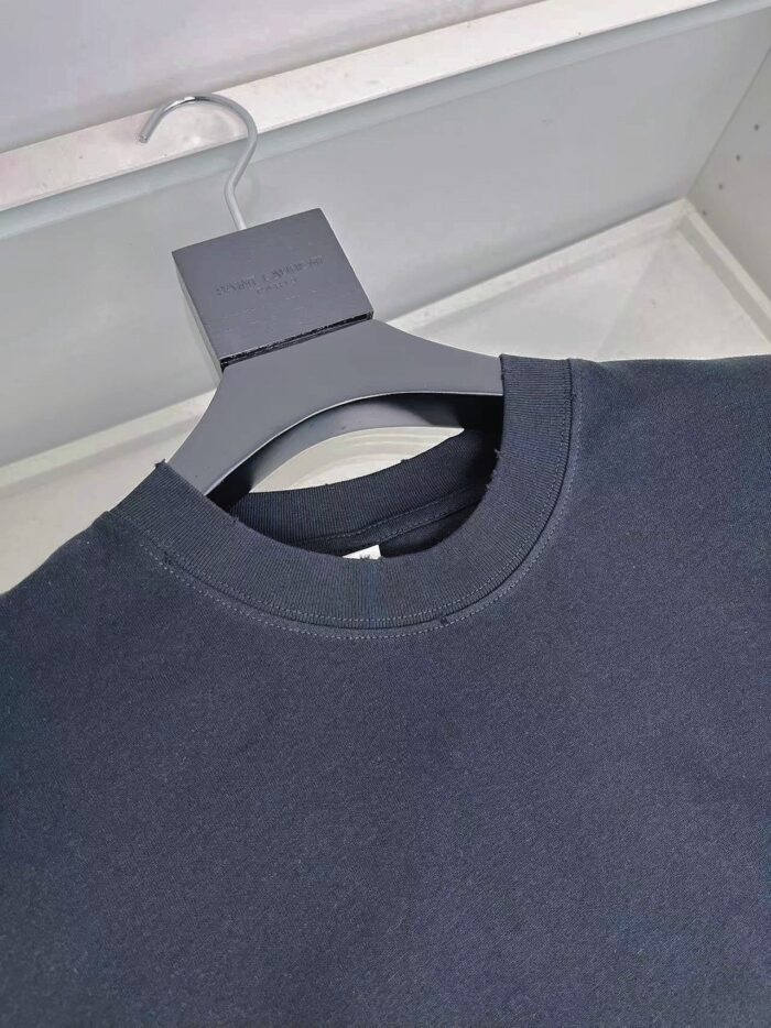 Maglietta nera minimalista su appendino in negozio, stile casual ed elegante.