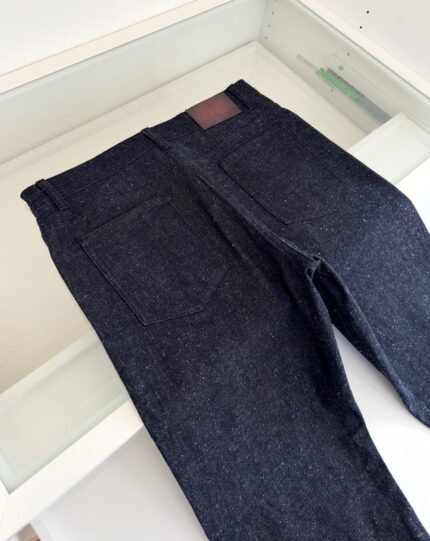 Jeans in denim scuro con tasche minimaliste e dettaglio in pelle, stile moderno e senza tempo.