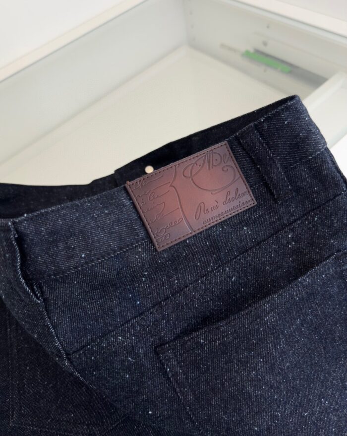 Jeans in denim scuro con patch in pelle e dettagli eleganti, stile classico e moderno.